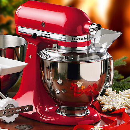 Robot de cuisine rouge avec accessoires devant une décoration de Noël.