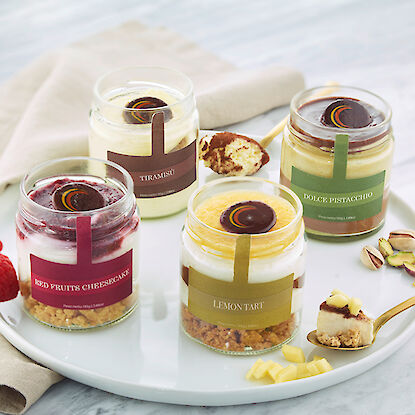 Quatre desserts en verre : Tiramisu, Cheesecake aux fruits rouges, Tarte au citron et Dolce Pistacchio.