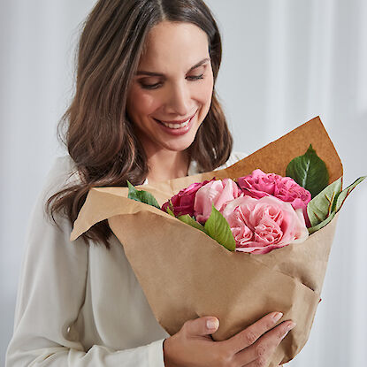 Dauerhaft blühender Blumenstrauß mit rosa Rosen und grünen Blättern