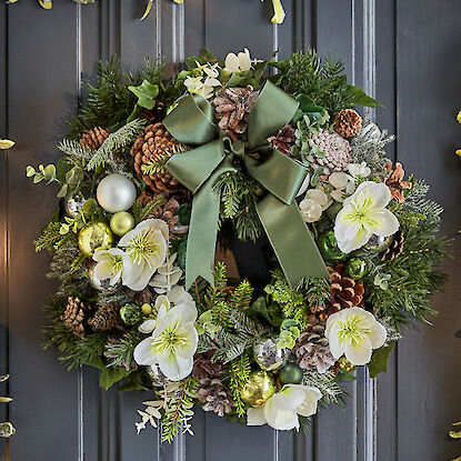 Festlicher Weihnachtskranz mit grüner Schleife, Tannenzapfen, weißen Blüten