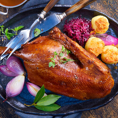 Knusprige gebratene Gans mit Rotkohl, gefüllten Kartoffeln und karamellisierten Zwiebeln