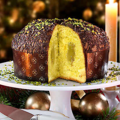 Angeschnittener Panettone mit Pistazien, festlich dekoriert.