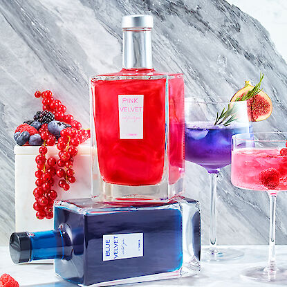 Zwei Flaschen "Pink Velvet" und "Blue Velvet" mit Beeren und Cocktails.