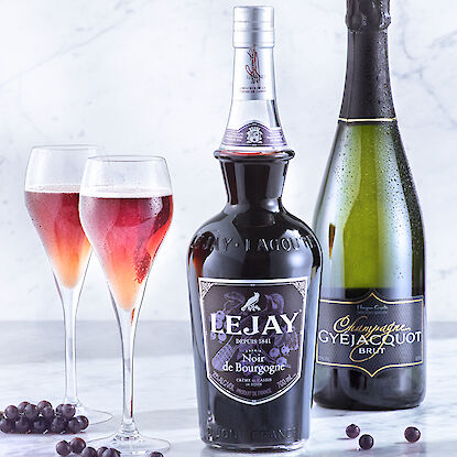 Flasche Lejay Cassis-Likör und Gyejacquot Champagner mit gefüllten Gläsern.