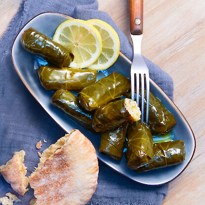 Feuilles de vigne farcies, servies avec des tranches de citron et du pain pita.