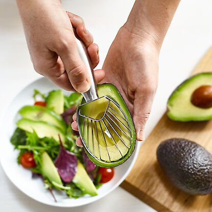 Avocado-Schneider in Aktion, schneidet eine reife Avocado