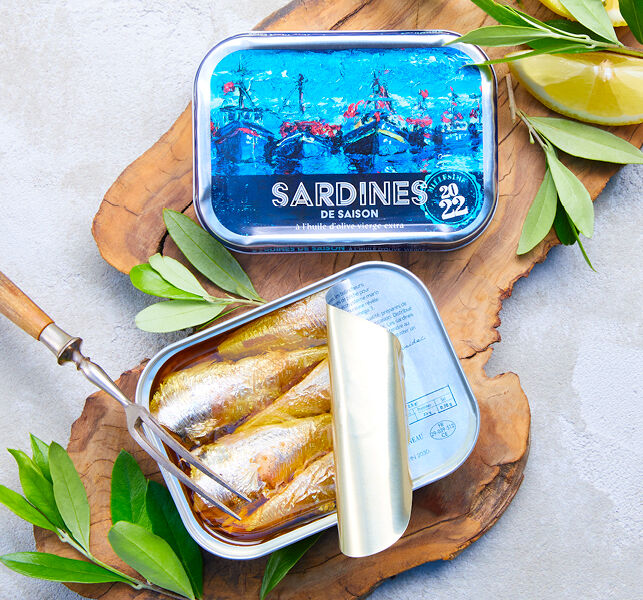 Boîte de sardines à l'huile d'olive, herbes fraîches et citron sur planche en bois.