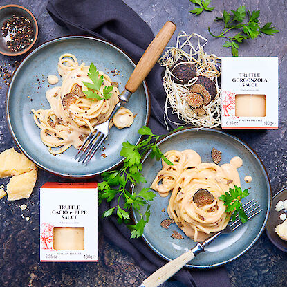 Pâtes à la sauce truffe sur assiettes, décorées d'herbes fraîches, parmesan et truffes, avec sauces emballées.