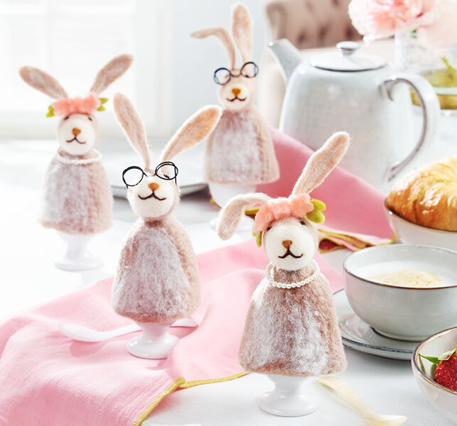 Lustige, gefilzte Osterhasen-Eierbecher mit Brillen und Schleifen auf einem Ostertisch als Gruppe aufgestellt