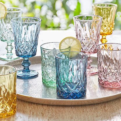 Farbenfrohe Trinkgläser aus Glas auf Tablett, perfekt für sommerliche Getränke