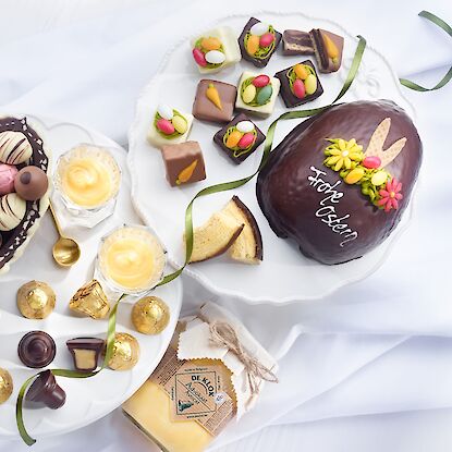 Ostertafel mit Schokoladenei, Pralinen, Baumkuchen