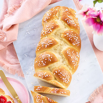 Brioche tressée fraîchement cuite avec des perles de sucre, servie avec de la confiture.