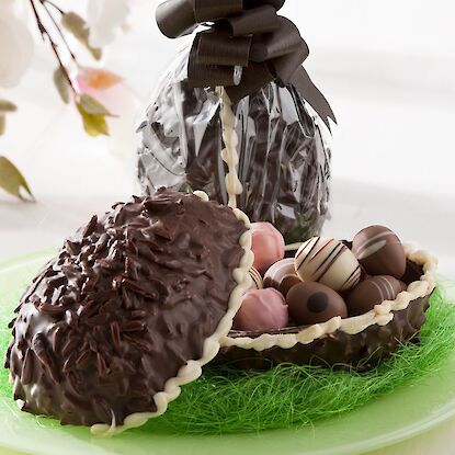 Œuf de Pâques en chocolat raffiné garni de pralines, présenté de façon décorative.