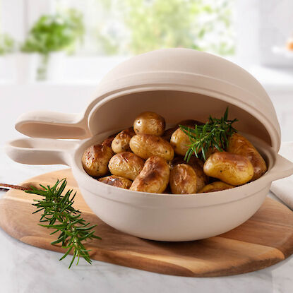 Pommes de terre rôties au romarin dans un plat en céramique sur une planche en bois.