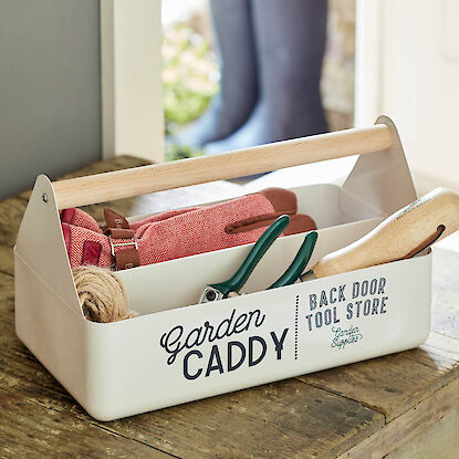 Weiße Gartencaddy-Box mit Handschuhen, Schere und Schnur auf Holztisch im Eingangsbereich
