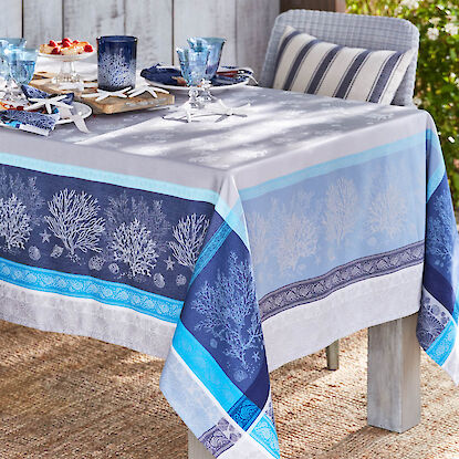 Festlich gedeckter Gartentisch mit maritimer Tischdecke in Blau- und Grautönen mit Korallenmotiv