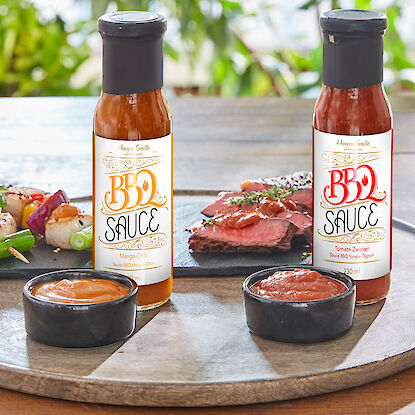 BBQ-Saucen Mango-Chili und Tomate-Zwiebel mit Fleisch, Dip-Schalen und Grillspießen serviert.
