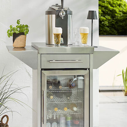 Getränkekühlschrank mit Zapfanlage, Biergläsern und Flaschen auf Terrasse.