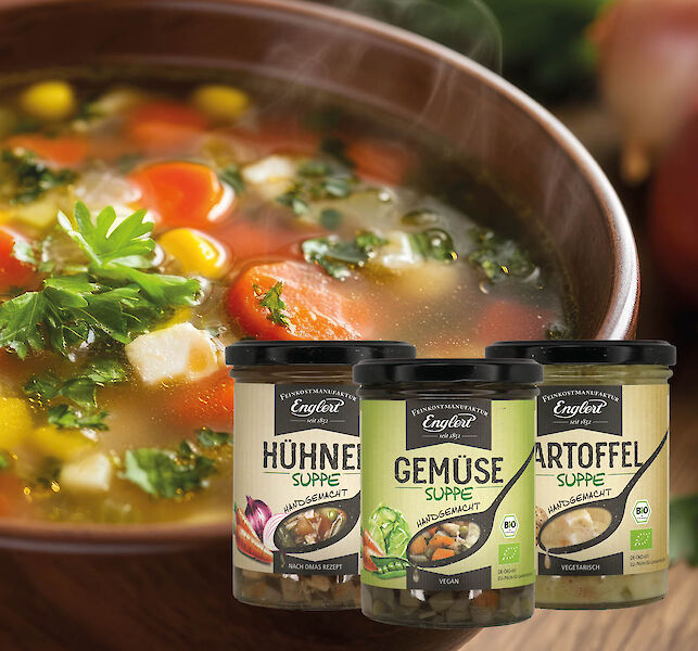 Drei Gläser Suppe vor dampfender Gemüsesuppe in Schale.