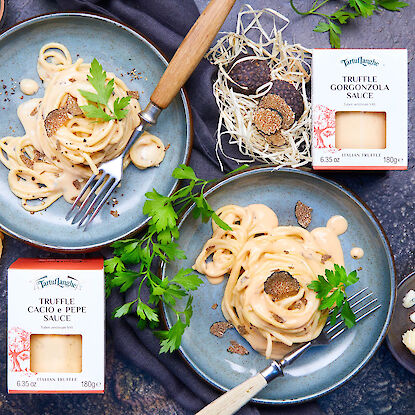 Pasta mit Trüffel-Käsesoße auf Tellern, dekoriert mit Petersilie und Verpackungen daneben.