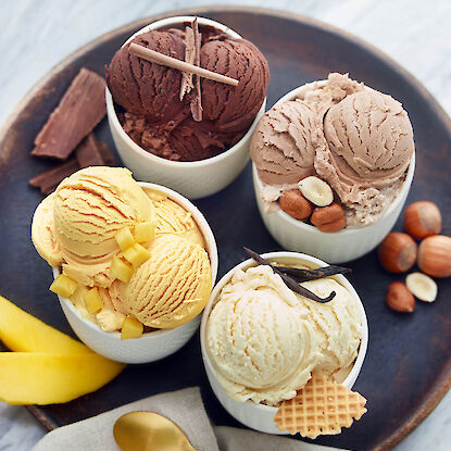 Quatre parfums de crème glacée dans des coupes : chocolat, noisette, mangue et vanille
