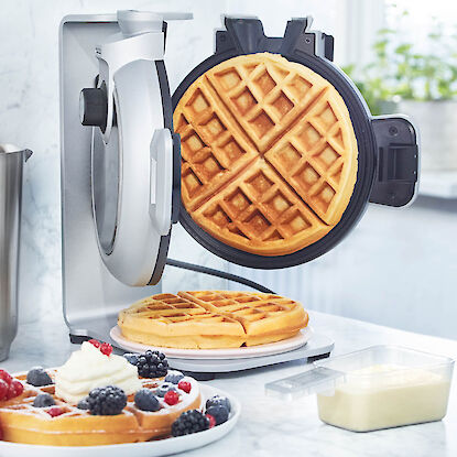 Gaufrier avec des gaufres fraîches et de la pâte sur le plan de travail de la cuisine