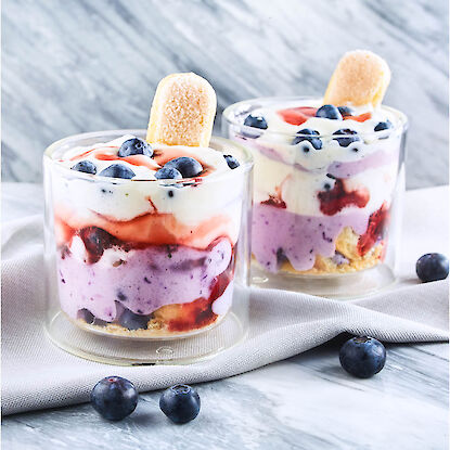 Dessert en verrine avec myrtilles, biscuit et couches de crème et coulis de fruits