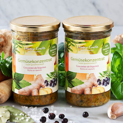 2 petits pots de concentré de légumes avec des légumes en arrière-plan