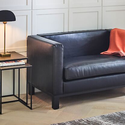 Schwarzes sofa und beisteltisch mit lampe im wohnzimmer