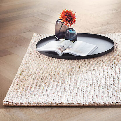 beige Teppich mit buch und einer Vase mit einer Roten Blume drin