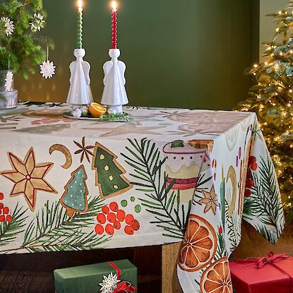 Tisch mit engel kerzenhalter weihnachts tischdecke einem Weihnachtsbaum und geschenken druhm herum verteilt