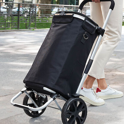 Femme en déplacement avec un chariot de courses