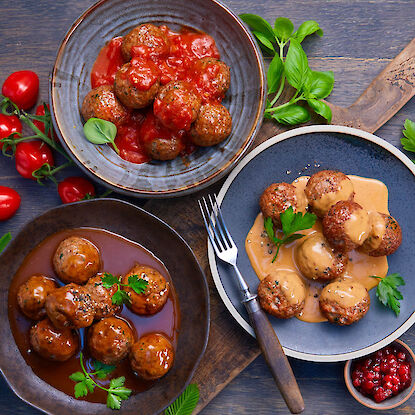 Trois variations de boulettes de viande avec différentes sauces – sauce tomate, sauce brune et sauce crémeuse – servies dans des assiettes rustiques avec des herbes fraîches et des accompagnements.