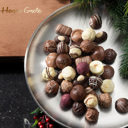 Pralines truffées exquises sur une assiette argentée, avec une boîte en bois en arrière-plan.