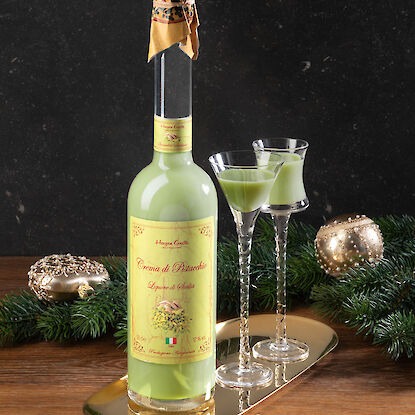 Liqueur fine de pistache sicilienne avec deux verres sur un plateau doré décoré de branches de sapin.