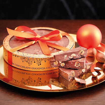 Gâteau en forme de Gianduja sur une assiette dorée sur une table en bois brun.