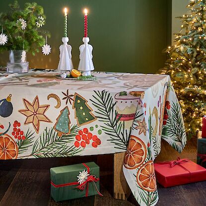 Weihnachtstisch mit bedruckter Tischdecke, Kerzenleuchtern, Tanne und Geschenken im festlichen Ambiente