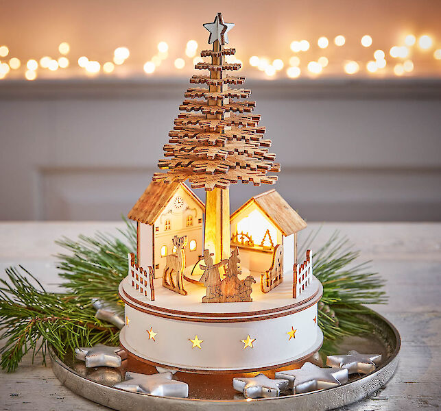 Beleuchtete Holzdekoration mit Weihnachtsbaum und Häuschen als stimmungsvolle Tischdekoration