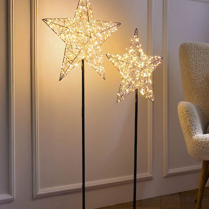 Leuchtsterne aus Drahtgeflecht auf Ständern als weihnachtliche Bodenbeleuchtung im Wohnzimmer