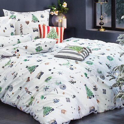 Weihnachtsbettwäsche in Weiß mit Tannenbaum-Motiven und dekorativen Kissen im festlich geschmückten Schlafzimmer
