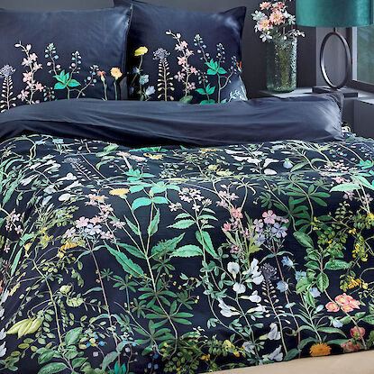 Bettwäsche in Schwarz mit buntem Blumenmuster, dekoriert mit passender Vase und Tischlampe