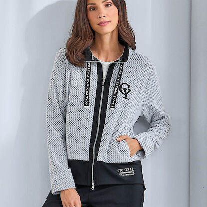 Frau in grauer Sportjacke mit schwarzer Hose, Modefoto vor hellem Hintergrund