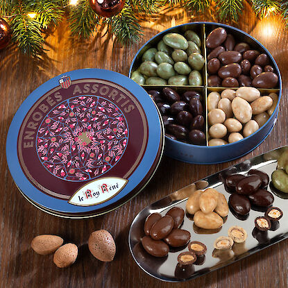 Bunte Schokoladendragees in runder Metalldose mit Mandeln und weihnachtlicher Dekoration