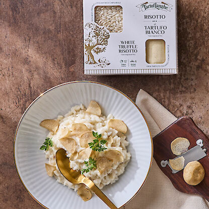 Cremiges Risotto mit weißen Trüffelscheiben und Verpackung daneben arrangiert