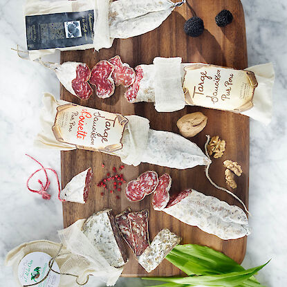 Verschiedene französische Salamis mit Walnüssen, Trüffeln und rosa Pfeffer auf Holzbrett