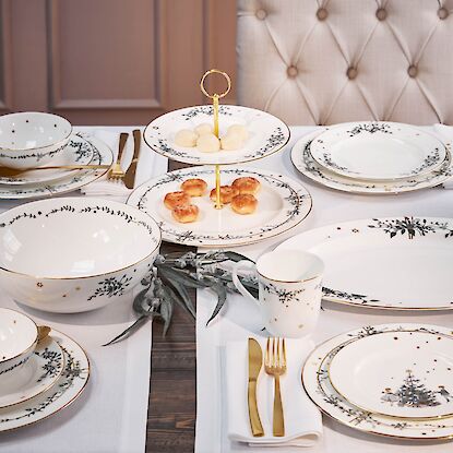 Weihnachtlich gedeckter Tisch mit weiß-goldenem Porzellan und Gebäck auf Etagere
