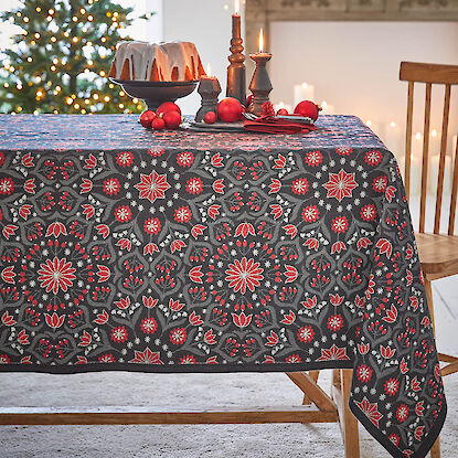 Dunkelgraue Tischdecke mit rotem Blumenmuster und Kerzen auf festlichem Tisch