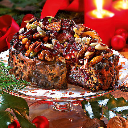 Traditioneller englischer Christmas Cake mit Nüssen und Trockenfrüchten – festlich dekoriert mit Kerzenlicht