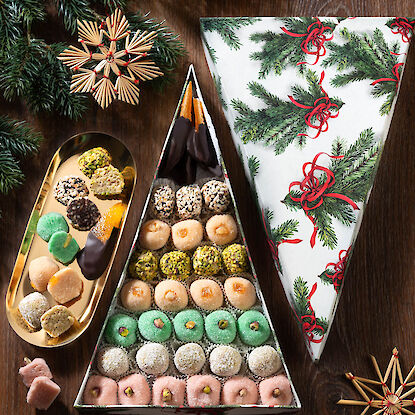 Dreieckige Geschenkbox mit buntem Marzipan und Pistazien, dekoriert mit Strohsternen und Tannenzweigen