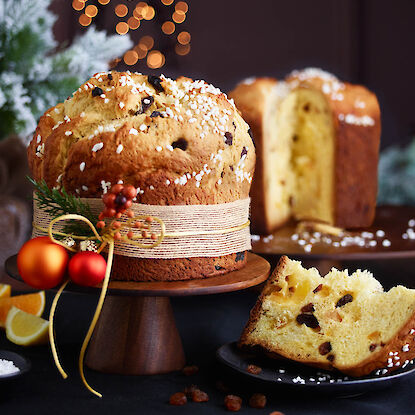 Italienischer Panettone mit Rosinen und Orangeat – saftiger Weihnachtskuchen auf Holzplatte festlich dekoriert
